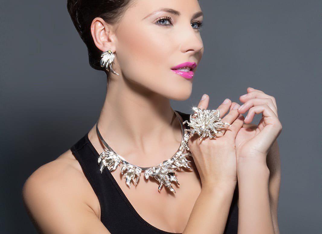 Elegante modelo de pelo oscuro con un vestido negro y una colección de joyas de plata