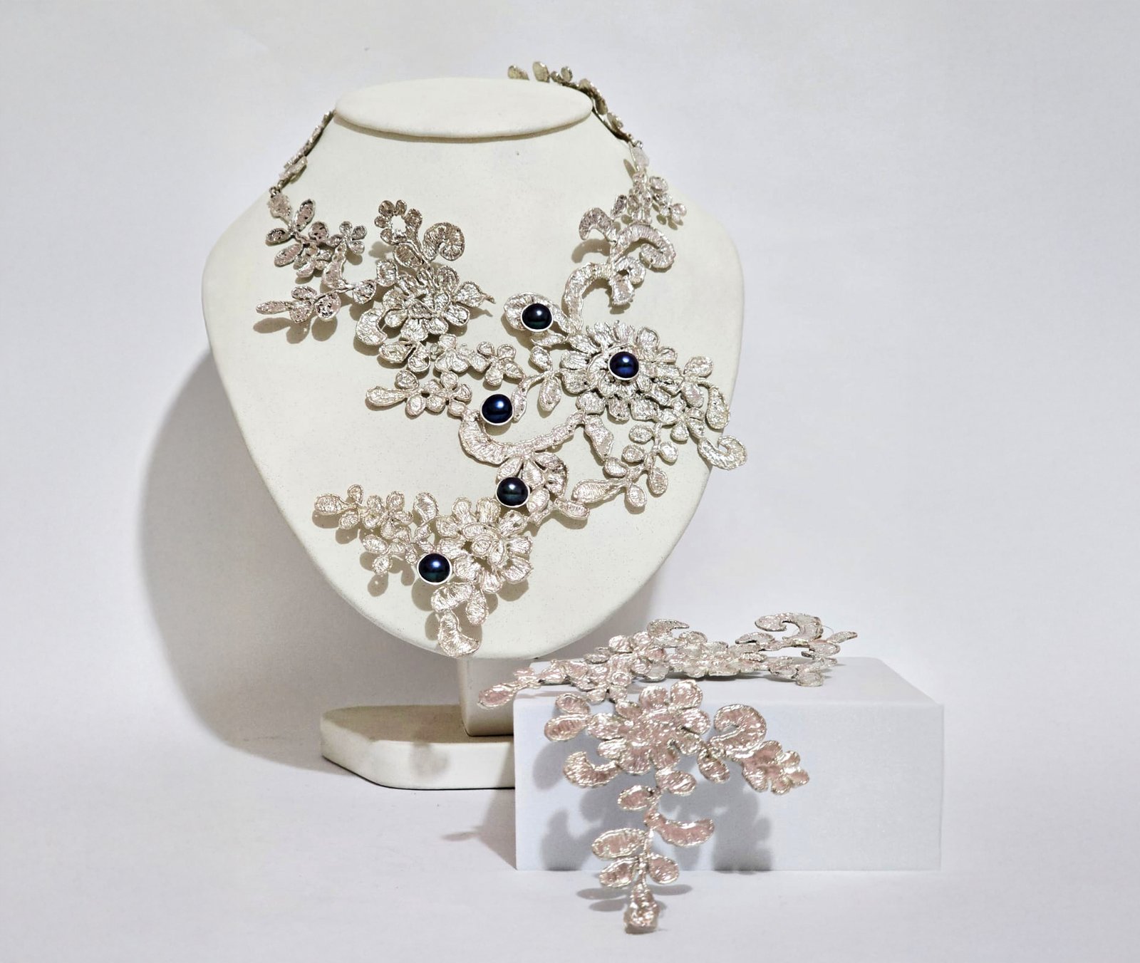 Collar y pendientes de plata sobre un busto blanco