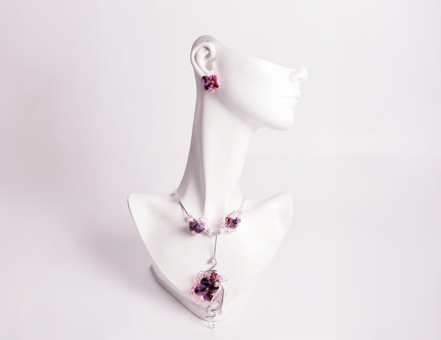 Una colección de joyas de plata con detalles de cristal de colores engastadas en un busto blanco