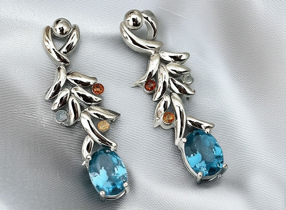 pendientes de plata con piedras de zafiro y aguamarina sobre fondo de tela de raso gris